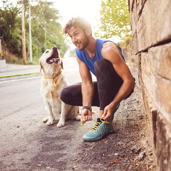 man with dog tying shoes before walk
